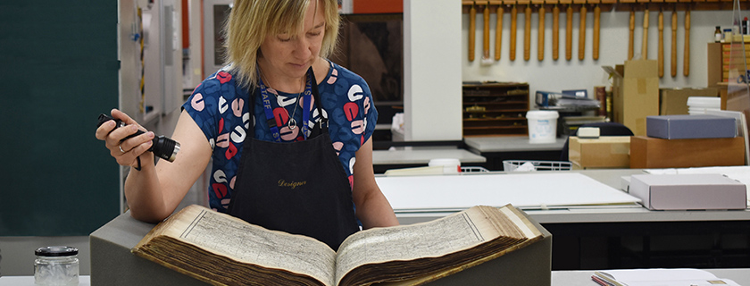 Conservator examining a book with a torch