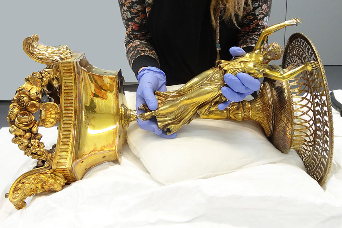 Conservator dissembling gilt silver stand