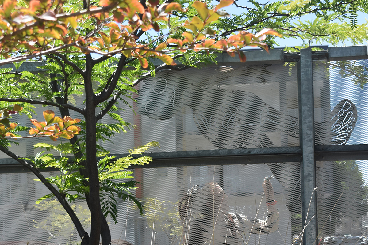 Conservator examining artwork on a fence at school