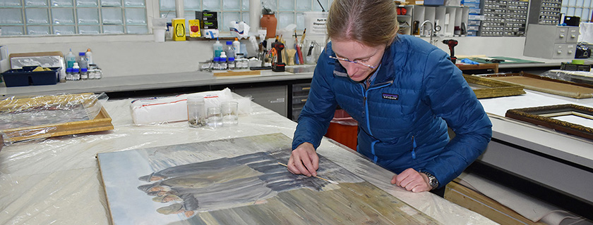 Conservator cleaning painting