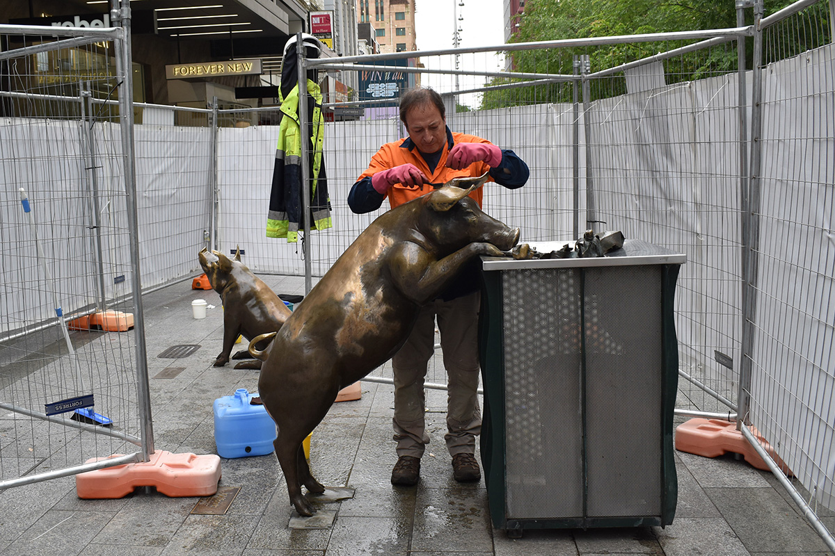 Conservator cleaning a sculpture after it has been vandalised