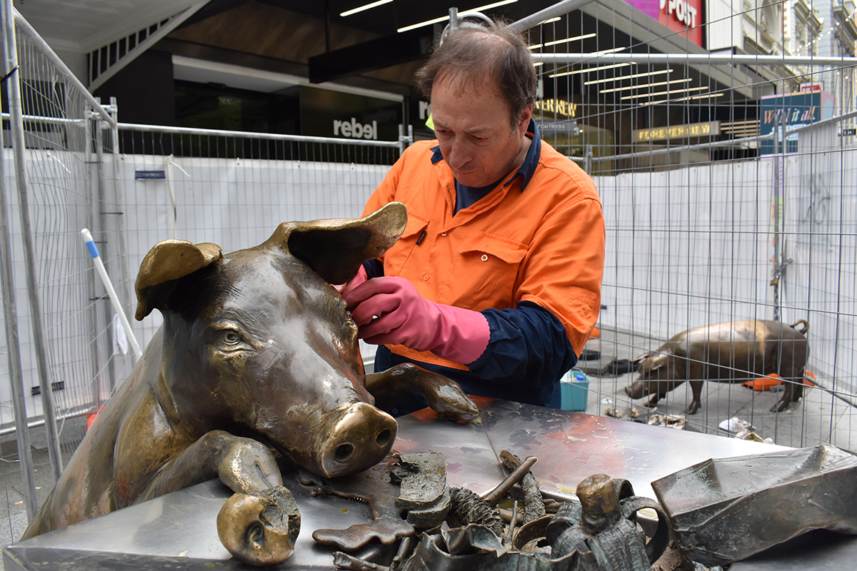 Conservator cleaning a sculpture after it has been vandalised