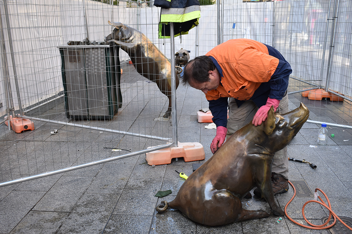 Conservator cleaning a sculpture after it has been vandalised