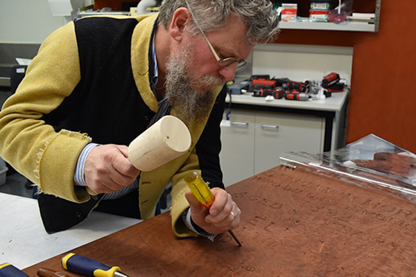 Conservator carving lettering on grave marker