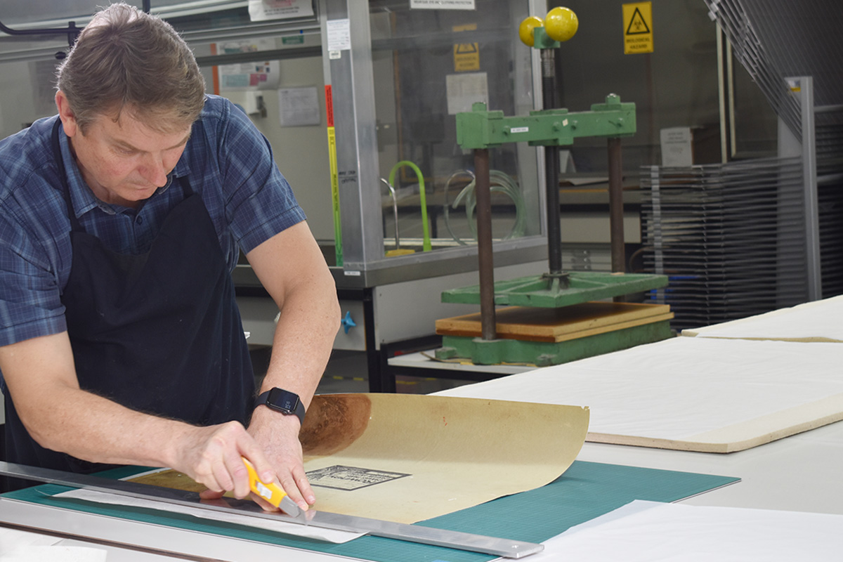 Conservator preparing and cutting paper