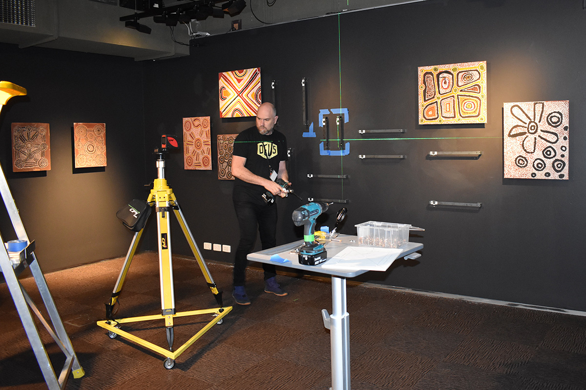 Exhibition designer installing brackets