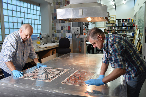Conservators flattening canvases