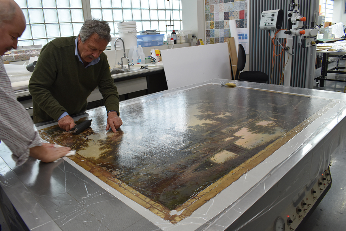 A painting being lined on a vacuum table
