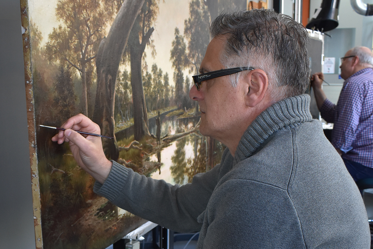 Conservator retouching the painting