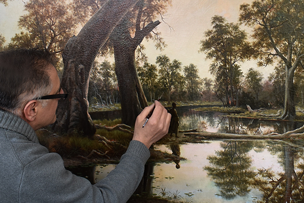 Conservator infilling paintings